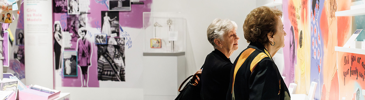 Two ladies looking at the girlhood exhibit.