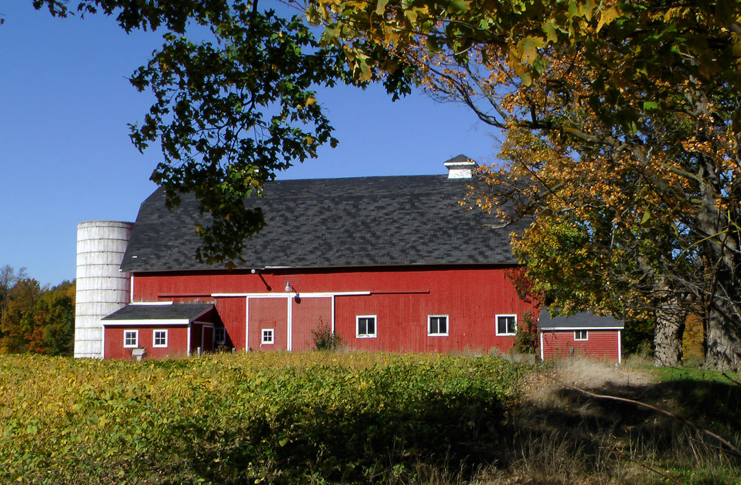 A red barn with a silo in the background.